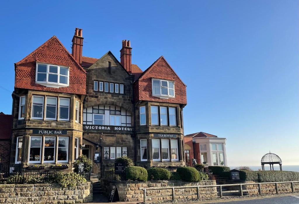 una vieja casa con el océano en el fondo en Victoria Hotel, en Whitby