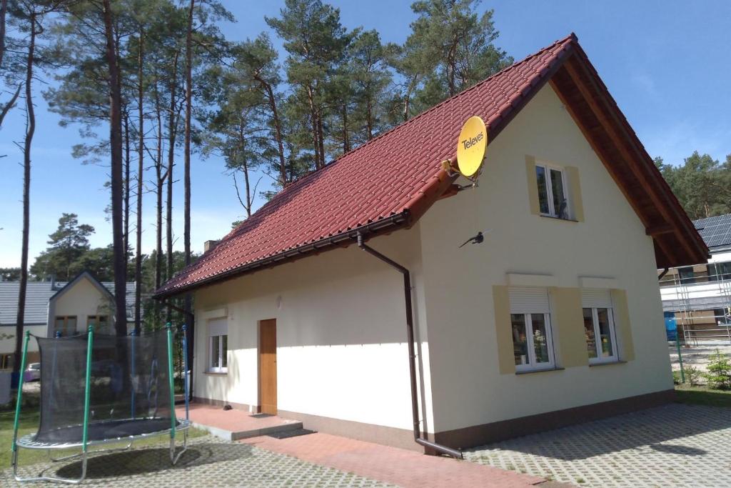 un pequeño edificio blanco con techo rojo en Big holiday home in Lukecin for 9 persons, en Łukęcin