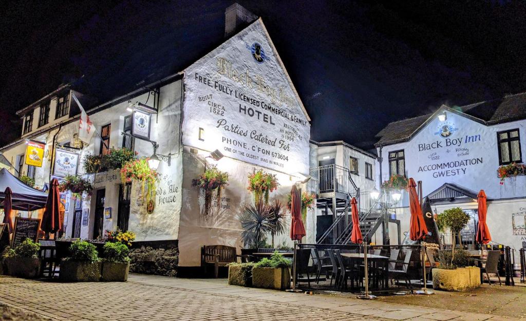 un edificio con mesas y sombrillas delante en The Black Boy Inn, en Caernarfon