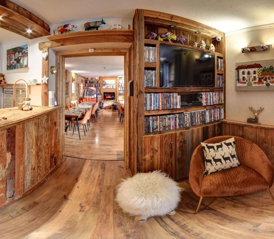 un soggiorno con pavimenti in legno e una libreria. di Hôtel Les Cimes a Megève