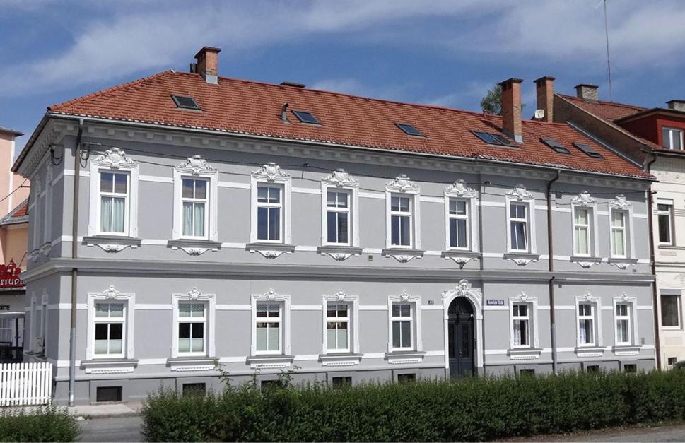 a large white building with a red roof at Stadtapartment WOHNEN48.AT in Klagenfurt