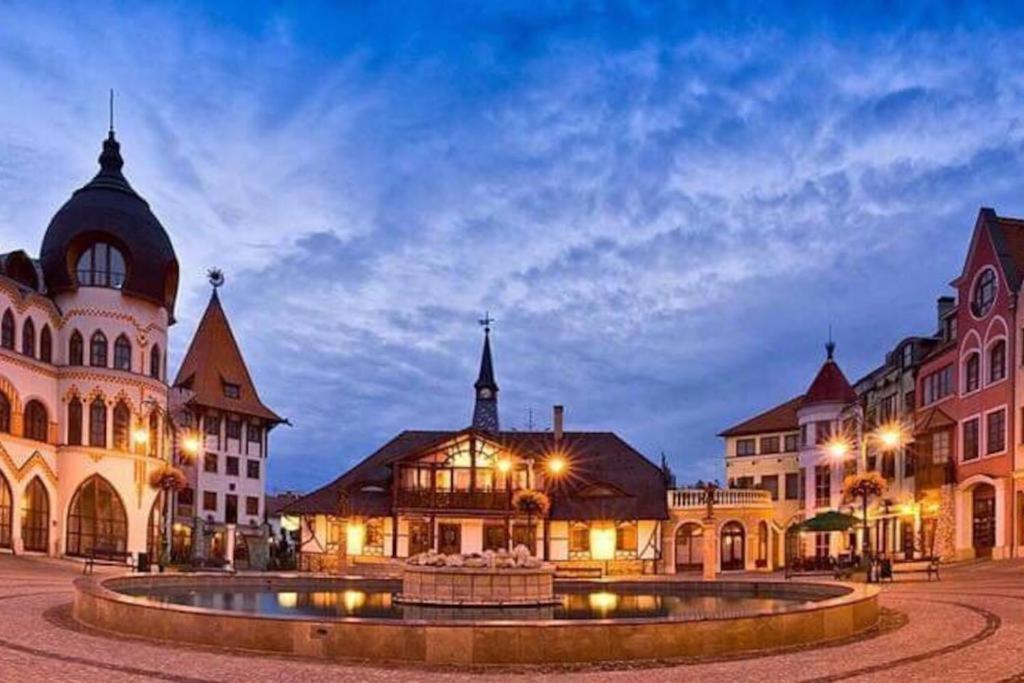 ein Stadtplatz mit einem Brunnen vor den Gebäuden in der Unterkunft Apartmán Lara in Komárno