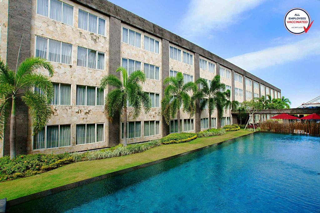 un bâtiment avec une piscine en face d'un bâtiment dans l'établissement Aston Denpasar Hotel & Convention, à Denpasar