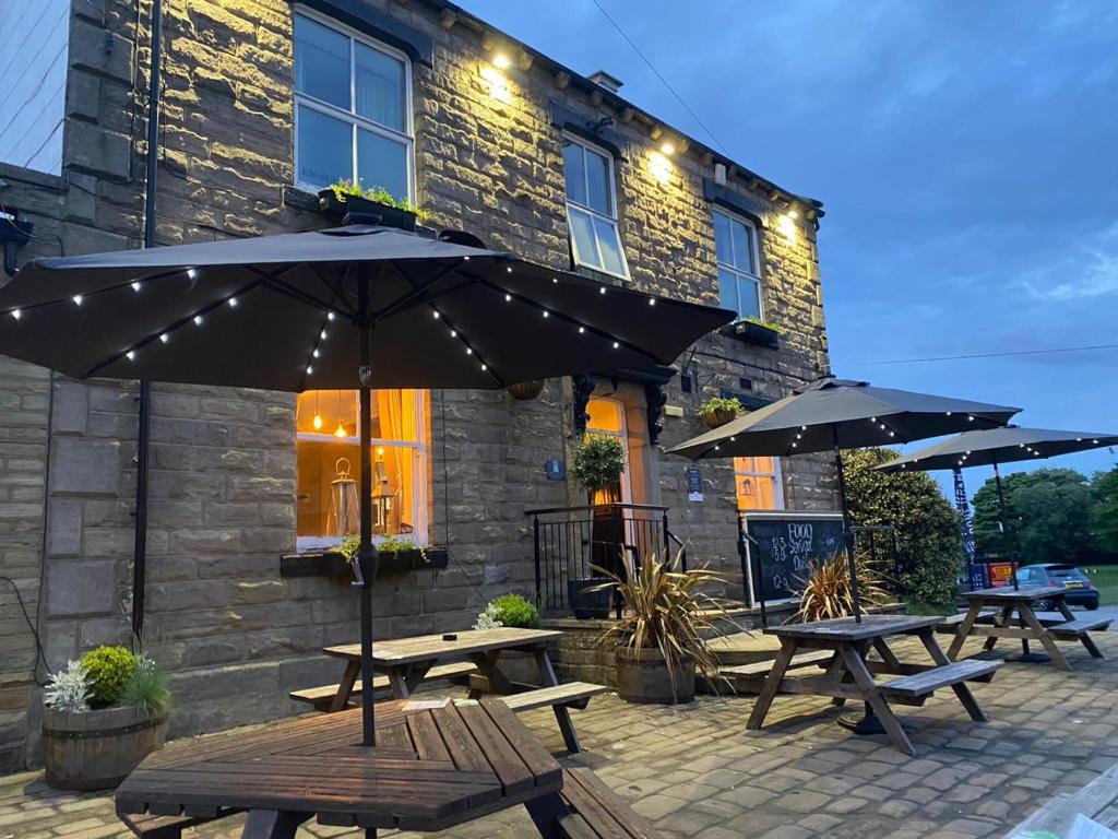 two picnic tables and umbrellas in front of a building at The White Swan, Yeadon in Yeadon