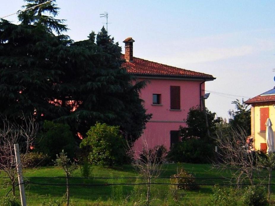 een roze huis in het midden van een veld bij Agriturismo La Prosciutta in Faenza