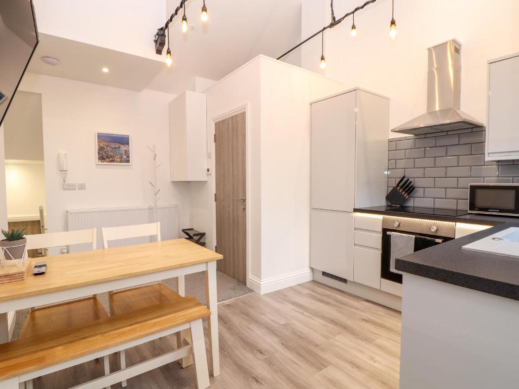 a kitchen with white cabinets and a wooden table at Battell Chambers in Camborne