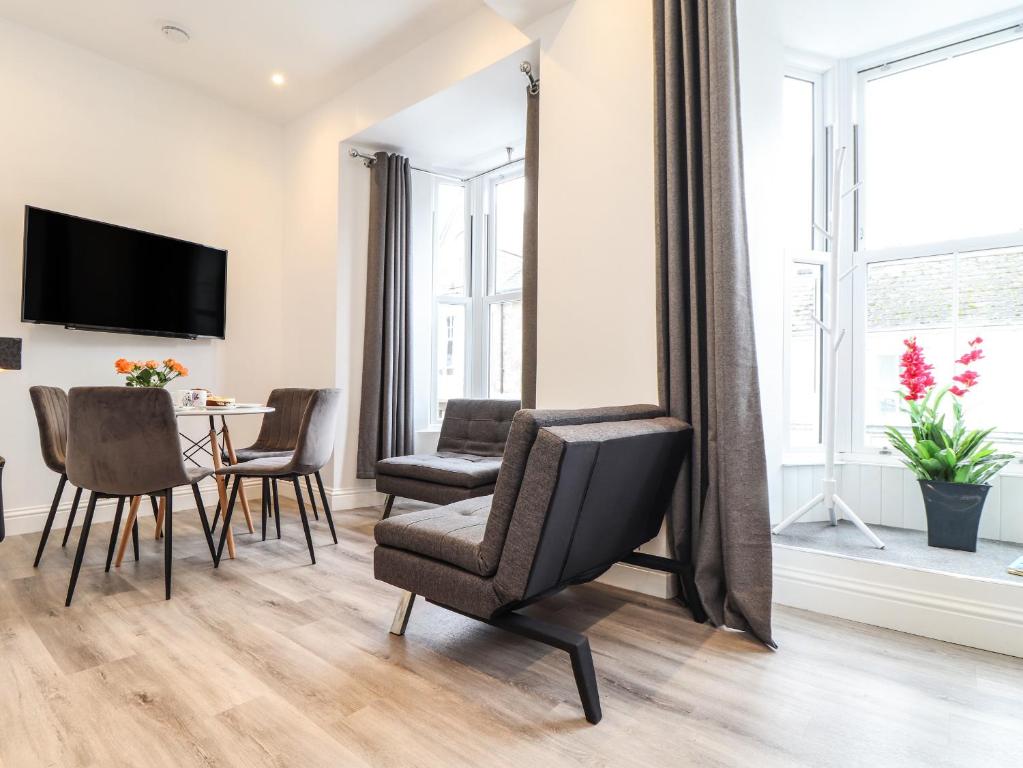 a living room with a table and chairs and a television at Baker Chambers in Camborne