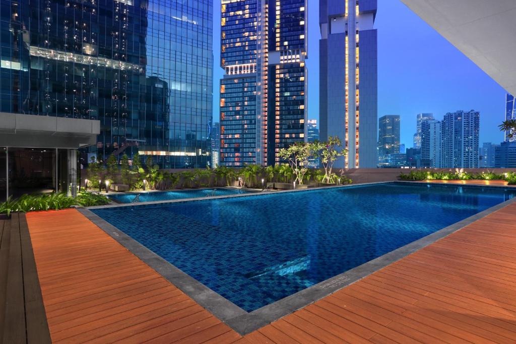 a swimming pool with a city skyline at night at Citadines Sudirman Jakarta in Jakarta