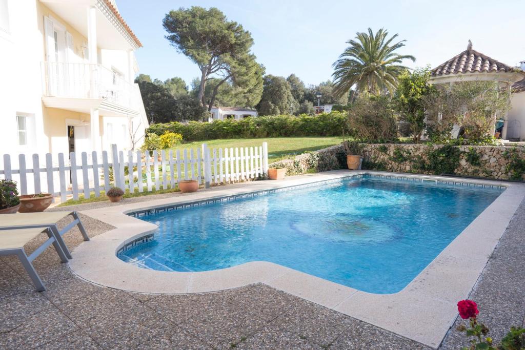 einen Pool in einem Garten mit einem weißen Zaun in der Unterkunft Orquideas in Cala Galdana