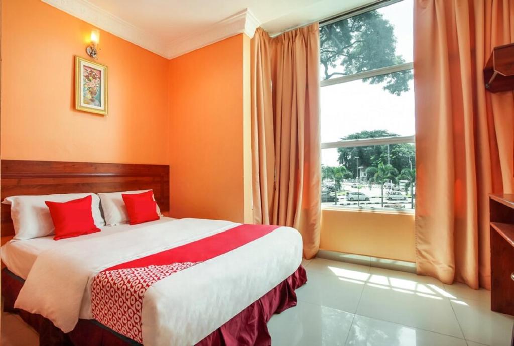 una camera da letto con pareti arancioni e un letto con cuscini rossi di My Town Hotel a Ipoh