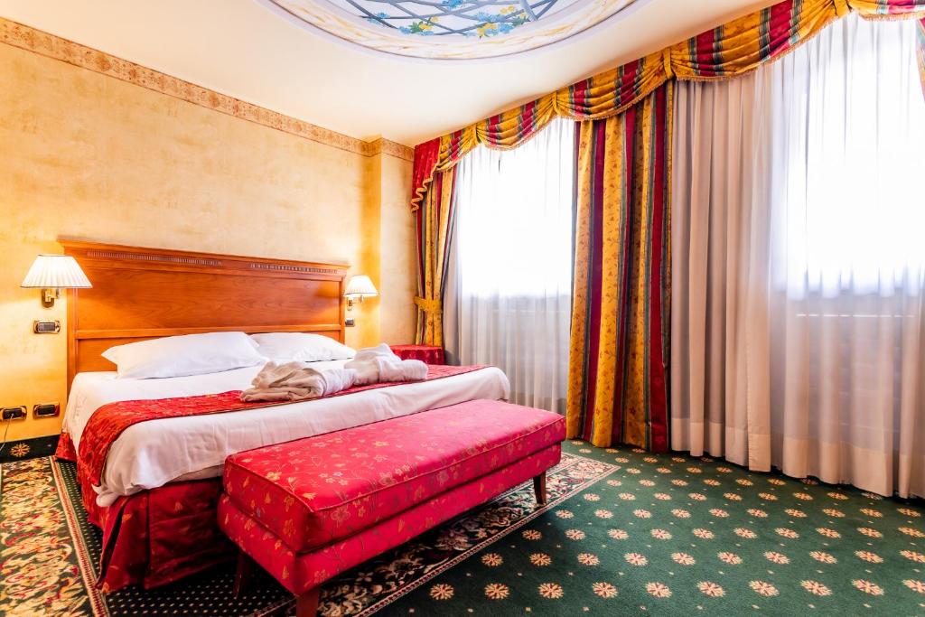 a hotel room with a bed and a red bench at Hotel Cristallo in Sestriere