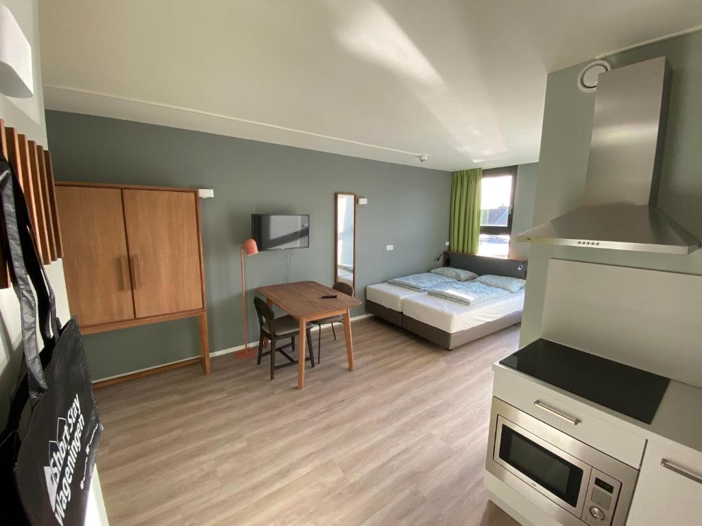 ein kleines Zimmer mit einem Bett und einem Tisch sowie einer Küche in der Unterkunft Short Stay Wageningen in Wageningen