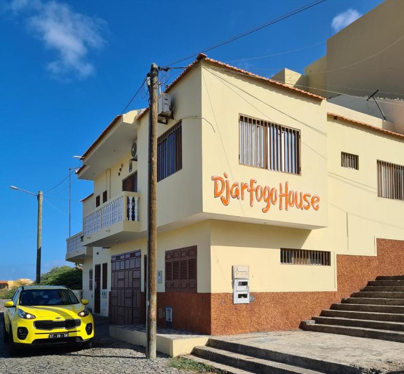 um carro amarelo estacionado em frente a um edifício em Djarfogo house em São Filipe