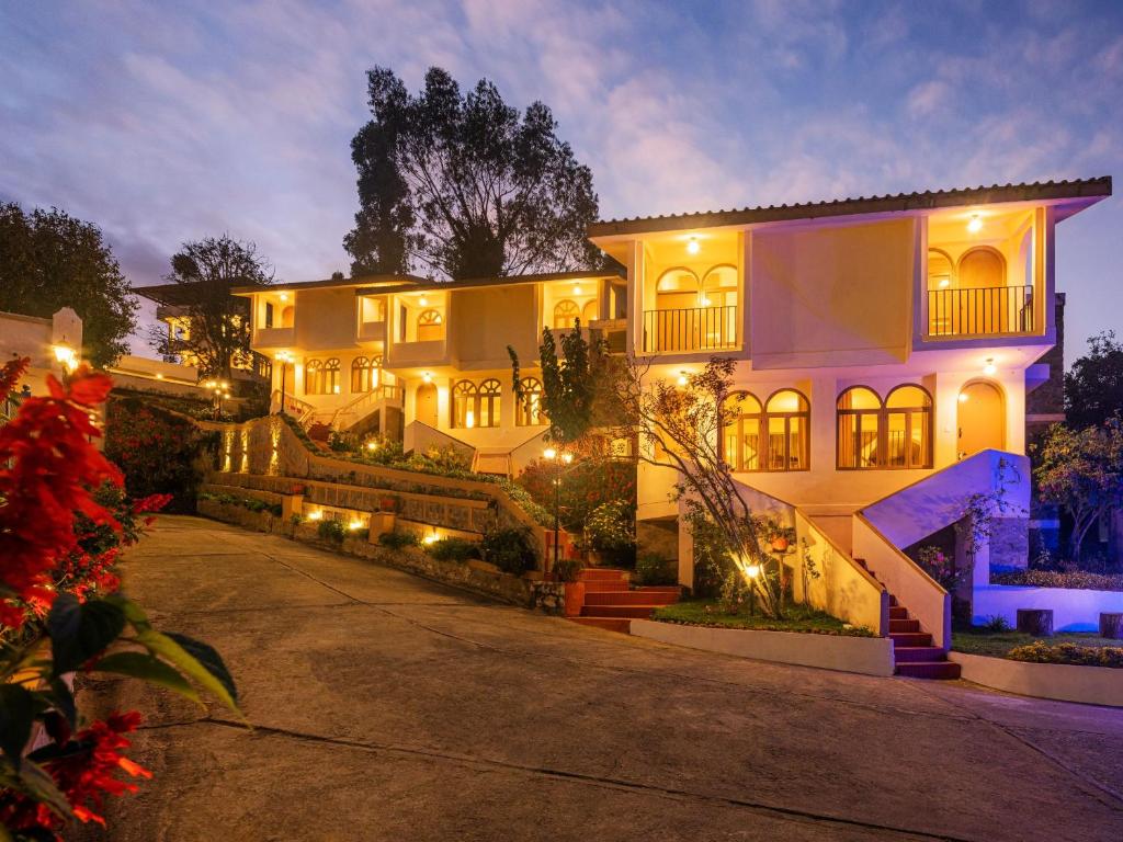 une grande maison blanche avec des lumières dans une allée. dans l'établissement Mango Hill Kodai, à Kodaikānāl