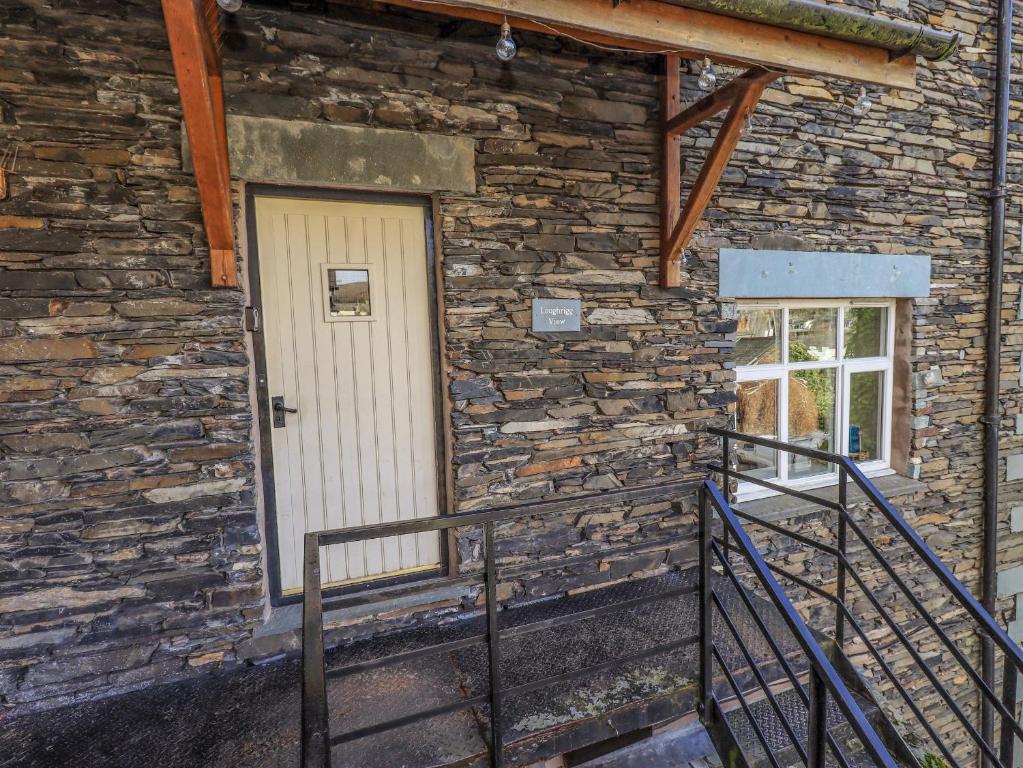 un edificio in pietra con una porta bianca e una finestra di Loughrigg View ad Ambleside