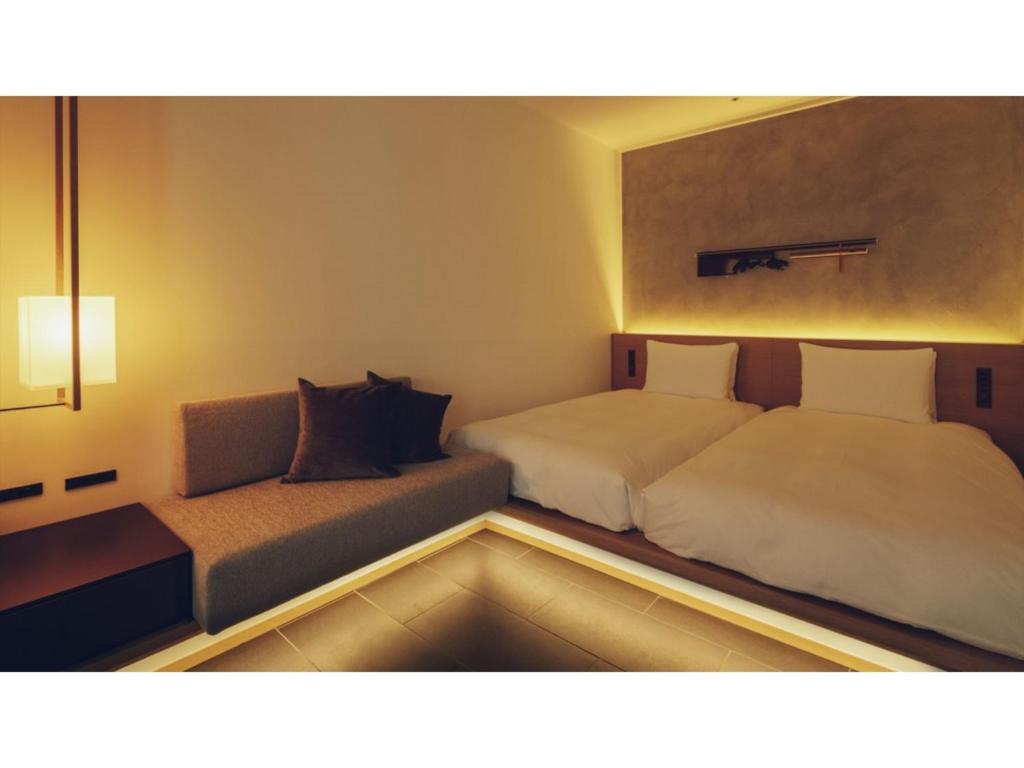 una camera d'albergo con due letti e un divano di nol kyoto sanjo - Vacation STAY 97692v a Kyoto