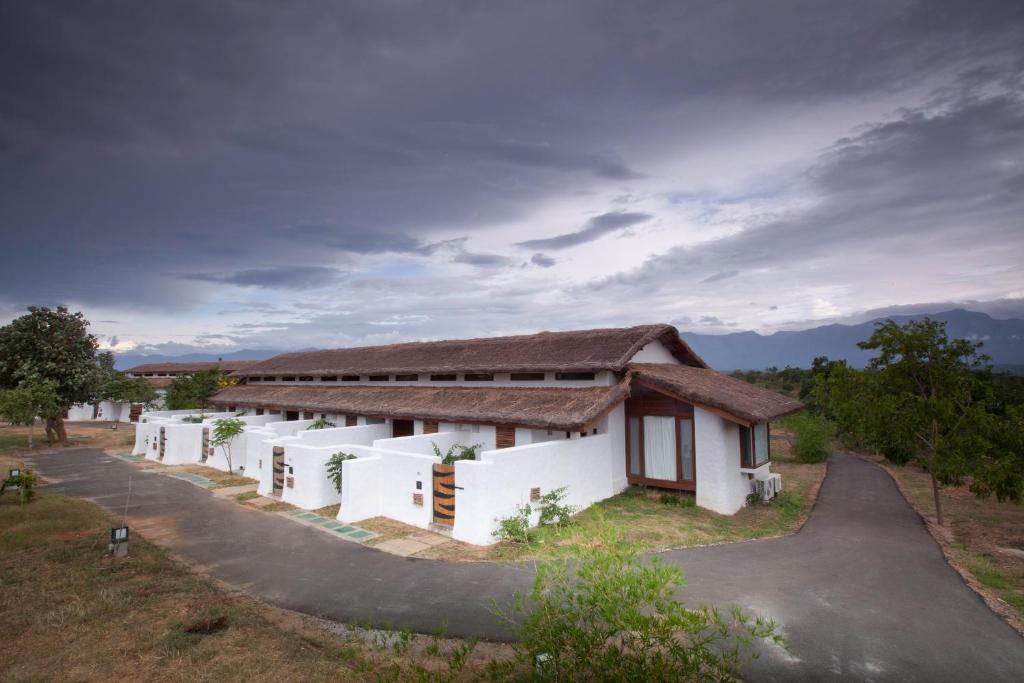 a house with a thatched roof on a road at The Serai Bandipur in Bandipūr