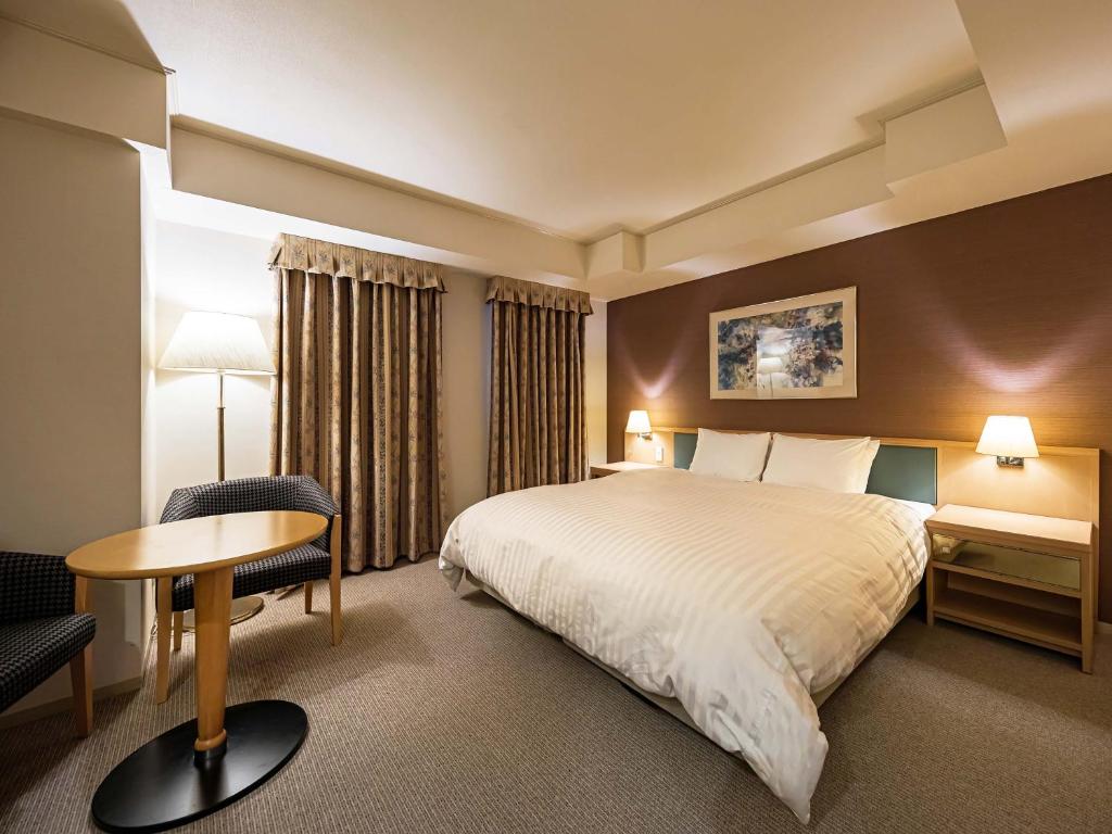 una camera d'albergo con letto, tavolo e sedia di Utsunomiya Tobu Hotel Grande a Utsunomiya