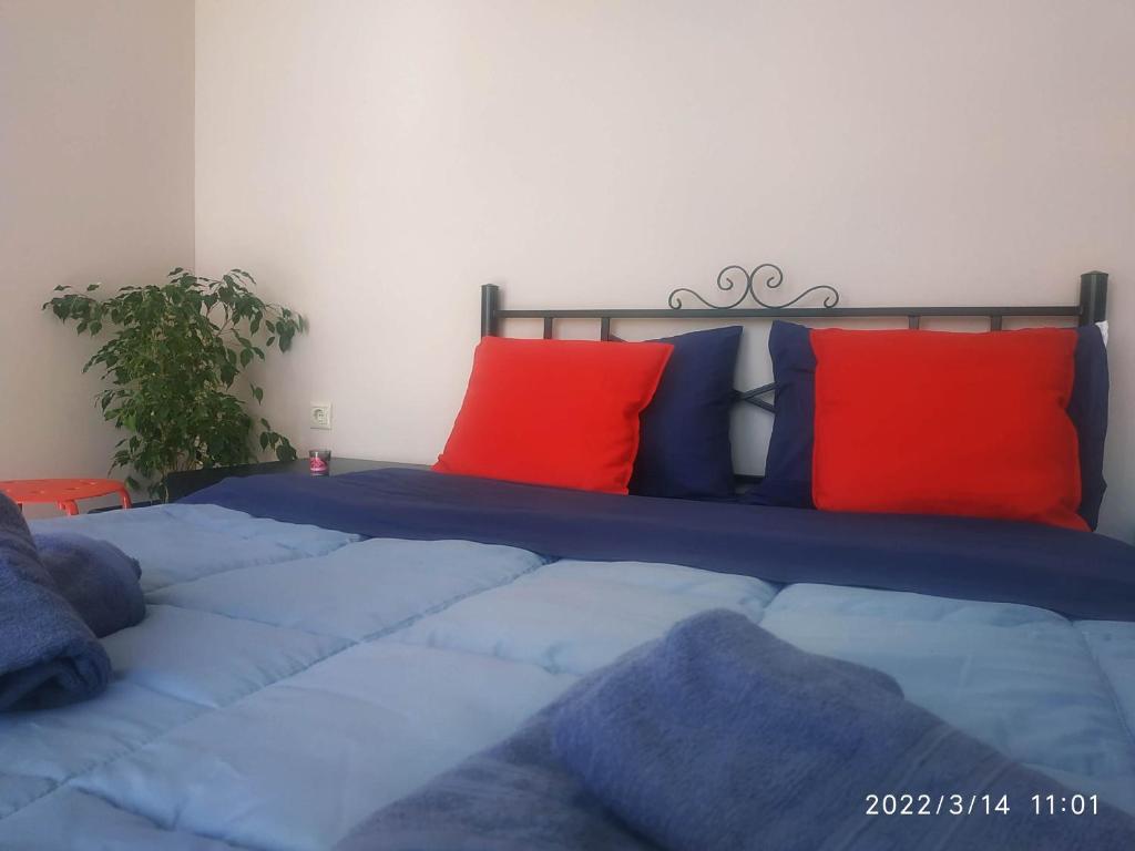 una camera da letto con letto con lenzuola blu e cuscini rossi di STUDIOS POSEIDONIA apartments 50 & 70 sqm with sea view a Korinthos