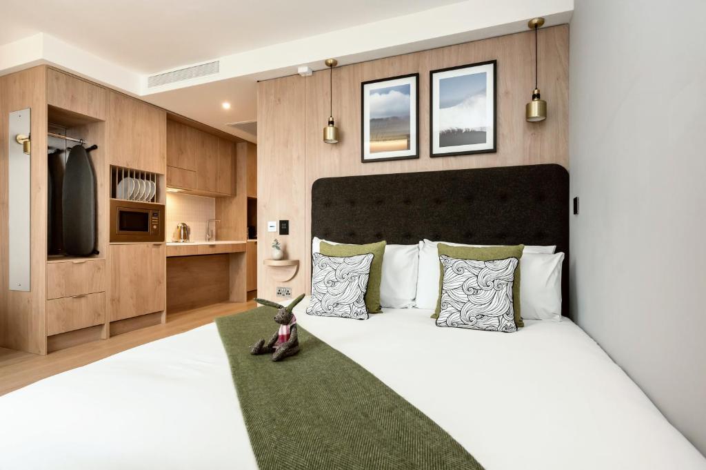 Schlafzimmer mit einem großen weißen Bett und einem grünen Teppich in der Unterkunft Wilde Aparthotels Manchester St. Peters Square in Manchester