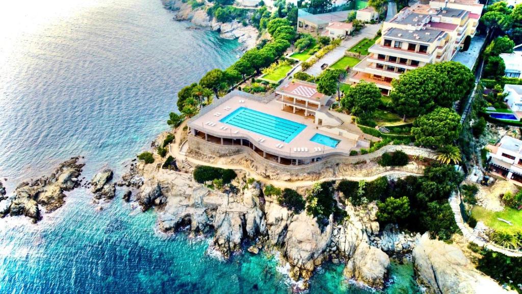 eine Luftansicht eines Hauses auf einer Klippe neben dem Wasser in der Unterkunft Almadraba Park Hotel in Roses