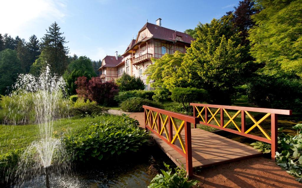 un pont sur un étang dans un jardin avec une maison dans l'établissement Jestřabí, à Luhačovice