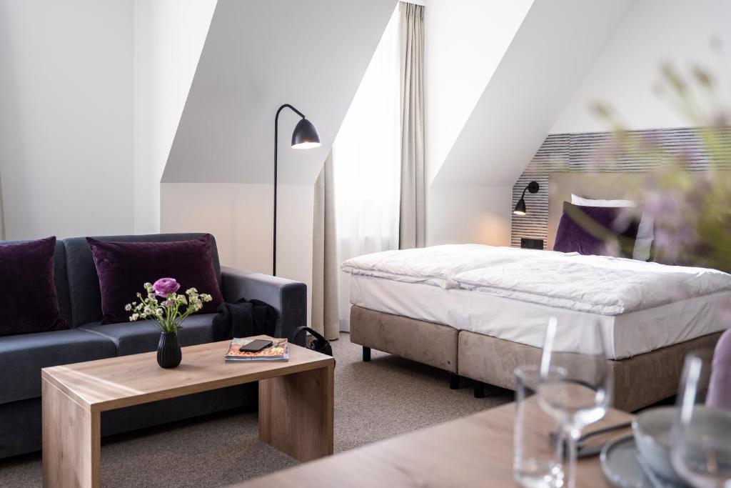 een woonkamer met een bed, een bank en een tafel bij maakt Hotel in Stralsund