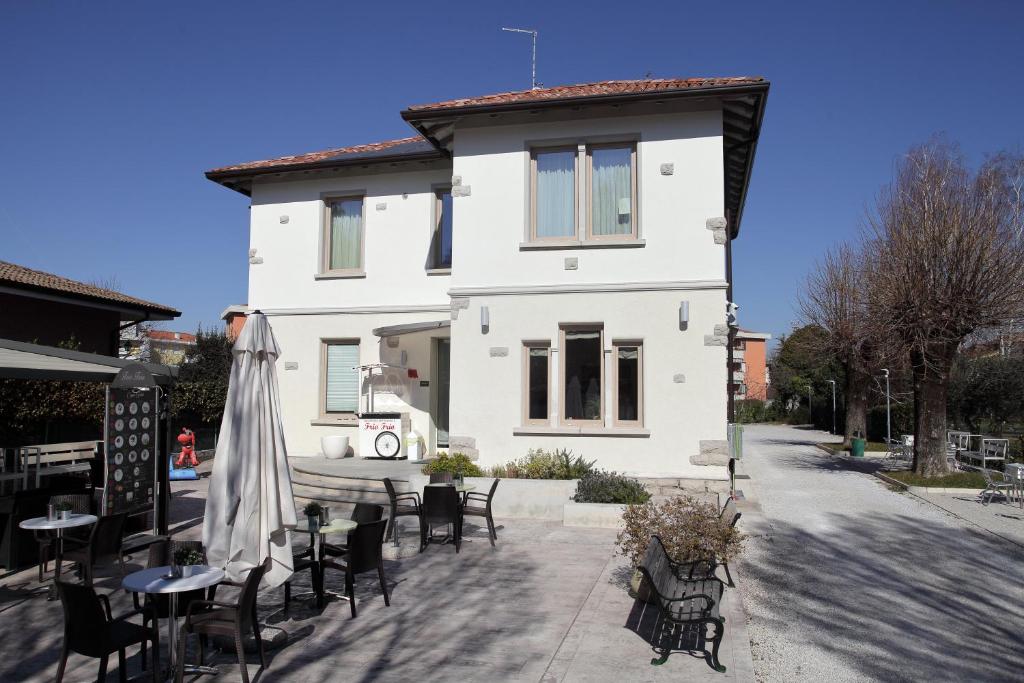 ein weißes Haus mit Tischen und Stühlen davor in der Unterkunft residence villa Frio Frio in Ronchi dei Legionari