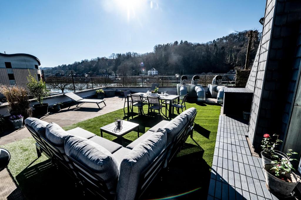 een patio met banken en een tafel op een dak bij Les 3 chapeaux Dinant in Dinant