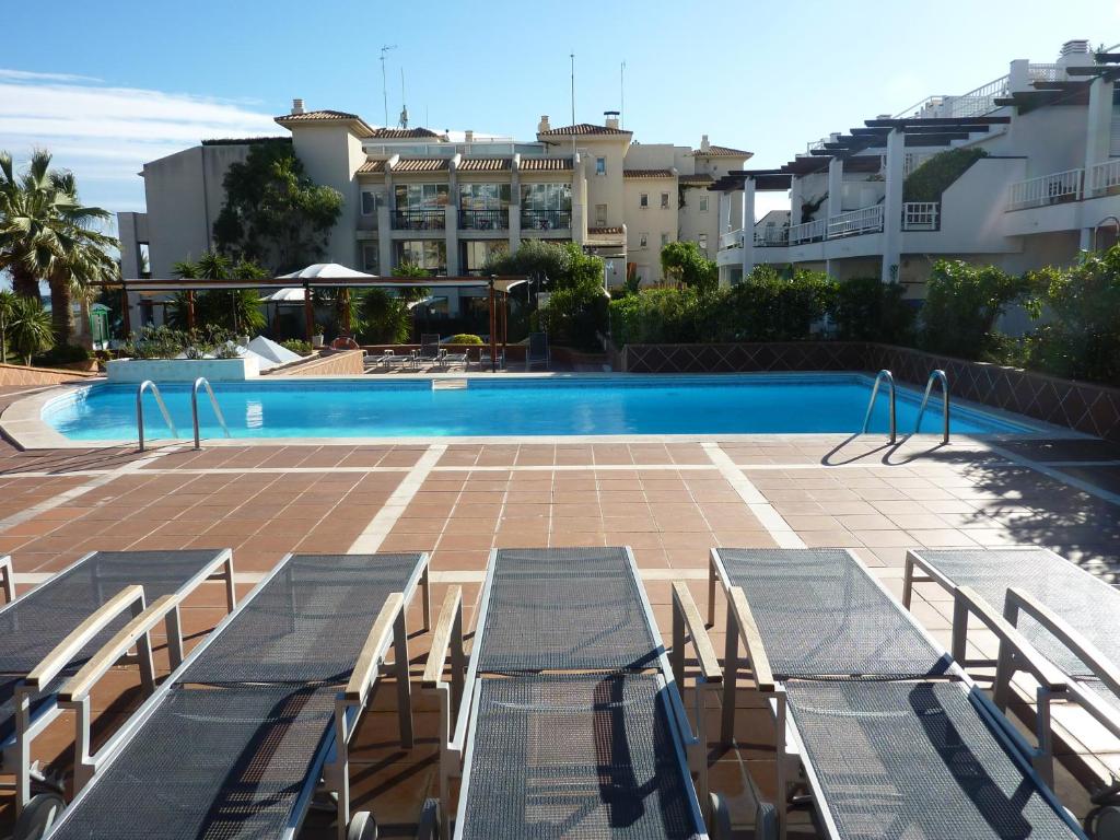 a swimming pool with tables and chairs in front of a building at Estela Barcelona in Sitges