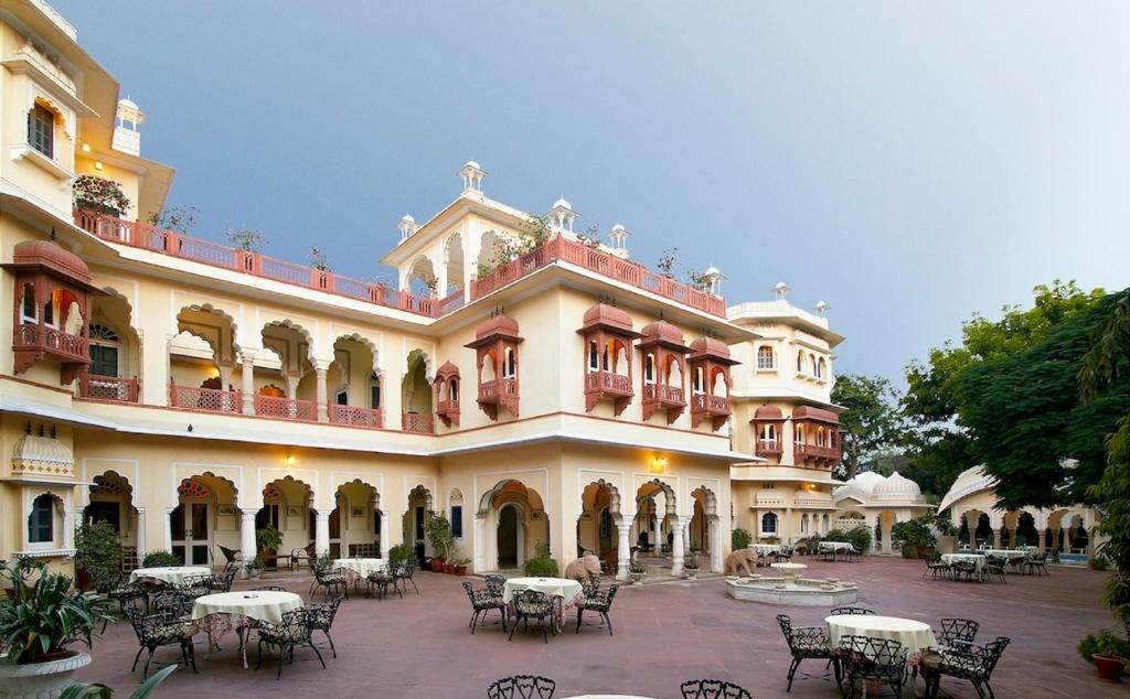 ein großes Gebäude mit Tischen und Stühlen im Innenhof in der Unterkunft Alsisar Haveli - Heritage Hotel in Jaipur