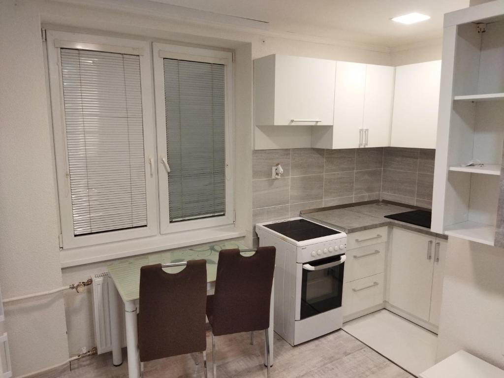 cocina con armarios blancos, mesa y sillas en Apartmán blízko centra, en Humenné