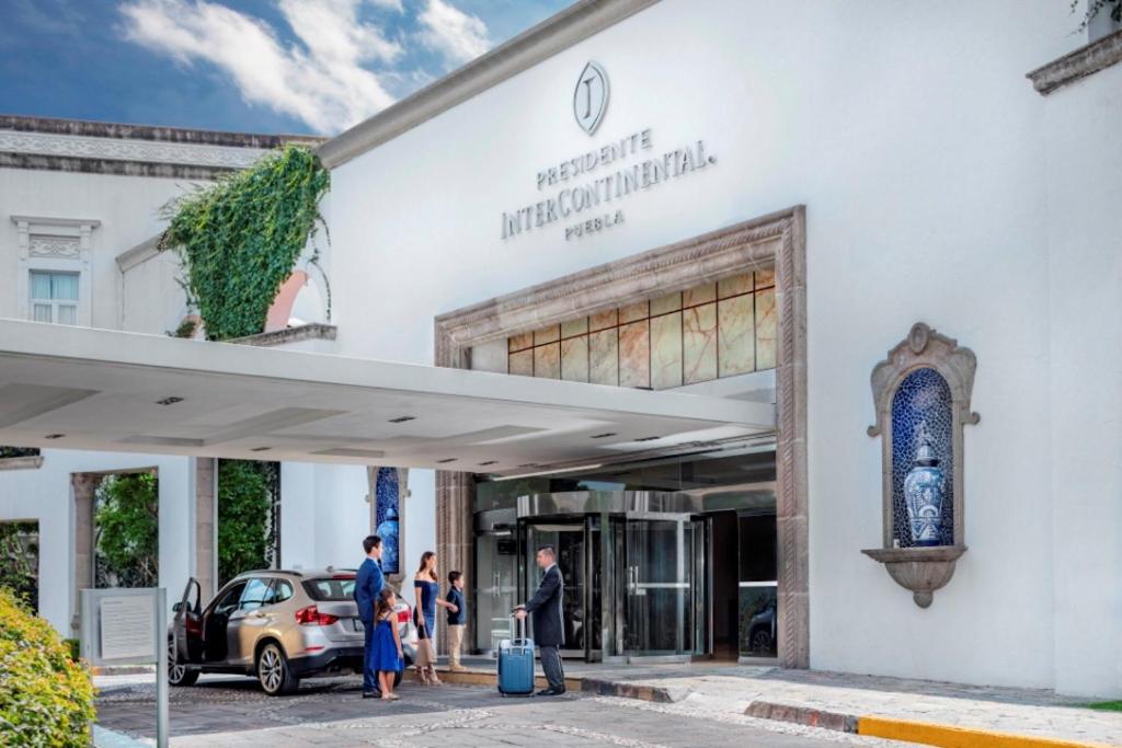 un grupo de personas parados fuera de un edificio en Presidente Intercontinental Puebla, an IHG Hotel, en Puebla