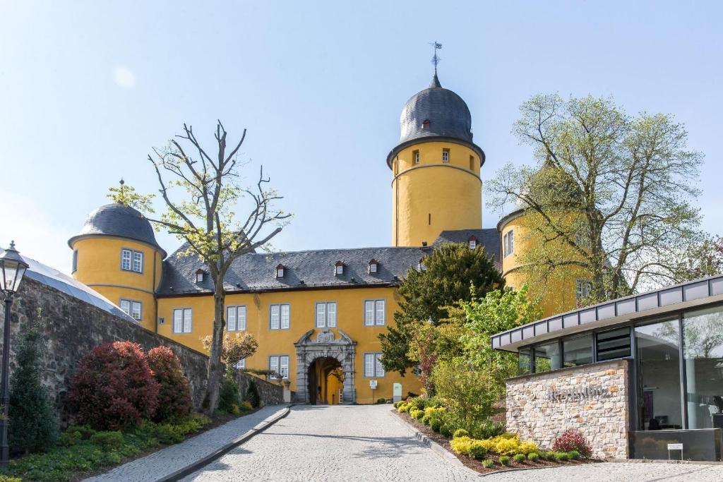 un grand bâtiment jaune avec deux tours dans l'établissement Hotel Schloss Montabaur, à Montabaur