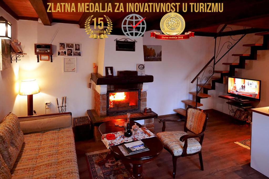 a living room with a fireplace and a couch and a table at Brvnare Platan - oaza prirode in Vrdnik