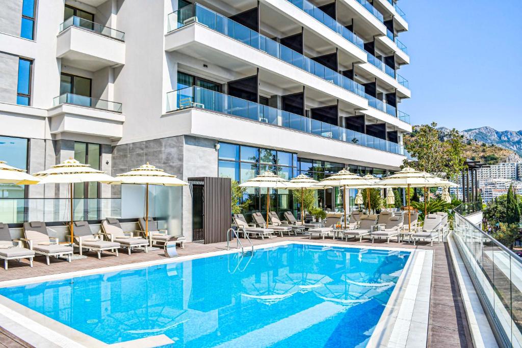 une image d'une piscine de l'hôtel avec des chaises et des parasols dans l'établissement Katamare Hotel, à Budva