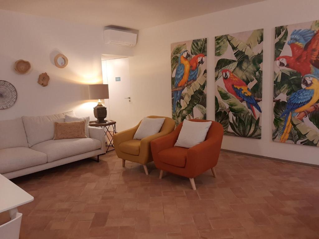 ein Wohnzimmer mit 2 Stühlen und Gemälden an der Wand in der Unterkunft Casa Algarbe in Faro