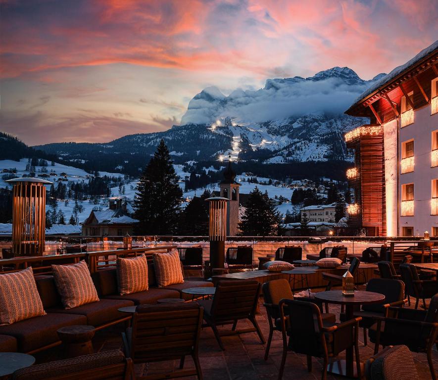 un patio del hotel con mesas, sillas y una montaña en Grand Hotel Savoia Cortina d'Ampezzo, A Radisson Collection Hotel, en Cortina dʼAmpezzo