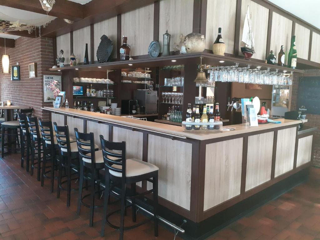 un bar avec des chaises et un comptoir dans un restaurant dans l'établissement Weinhaus Hotel, à Norddeich