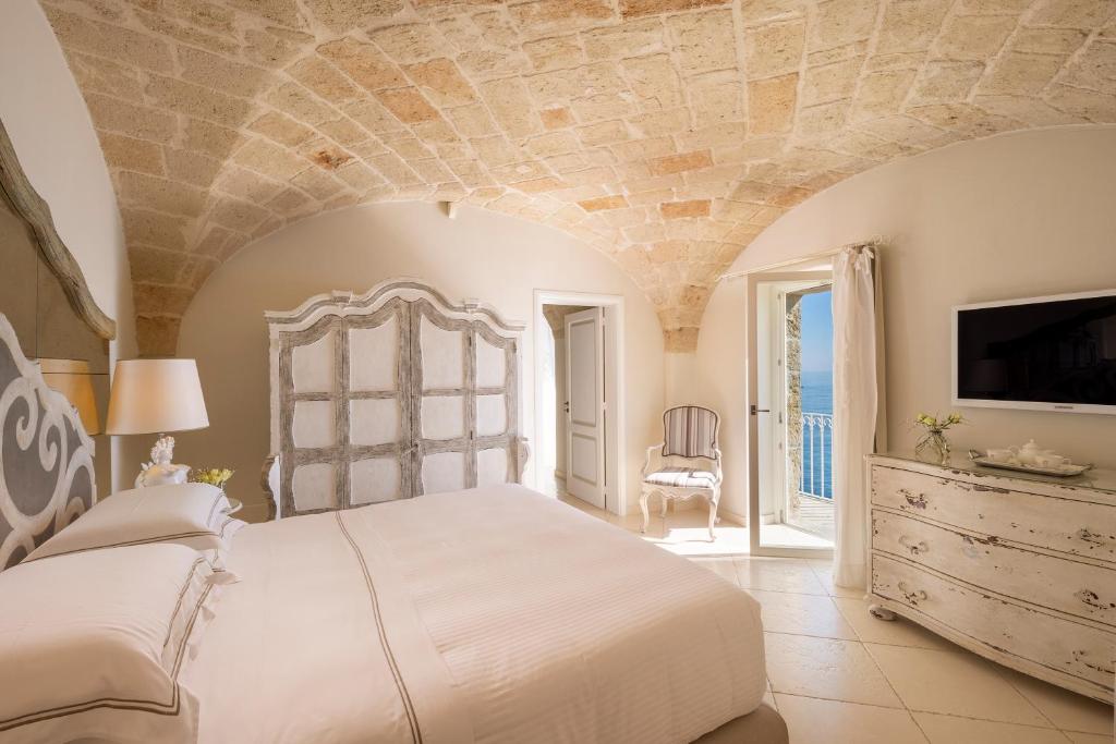 1 dormitorio con 1 cama blanca grande y TV en Hotel Don Ferrante, en Monopoli