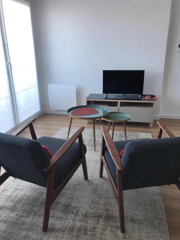 - un salon avec deux chaises et une table dans l'établissement APPARTEMENT NEUF ET BIEN SITUE AVEC UN CLASSEMENT, à Saint-Malo