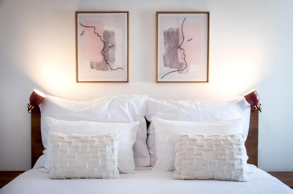 uma cama com almofadas brancas e duas fotografias na parede em bed&breakfast Bohemian em Rovinj