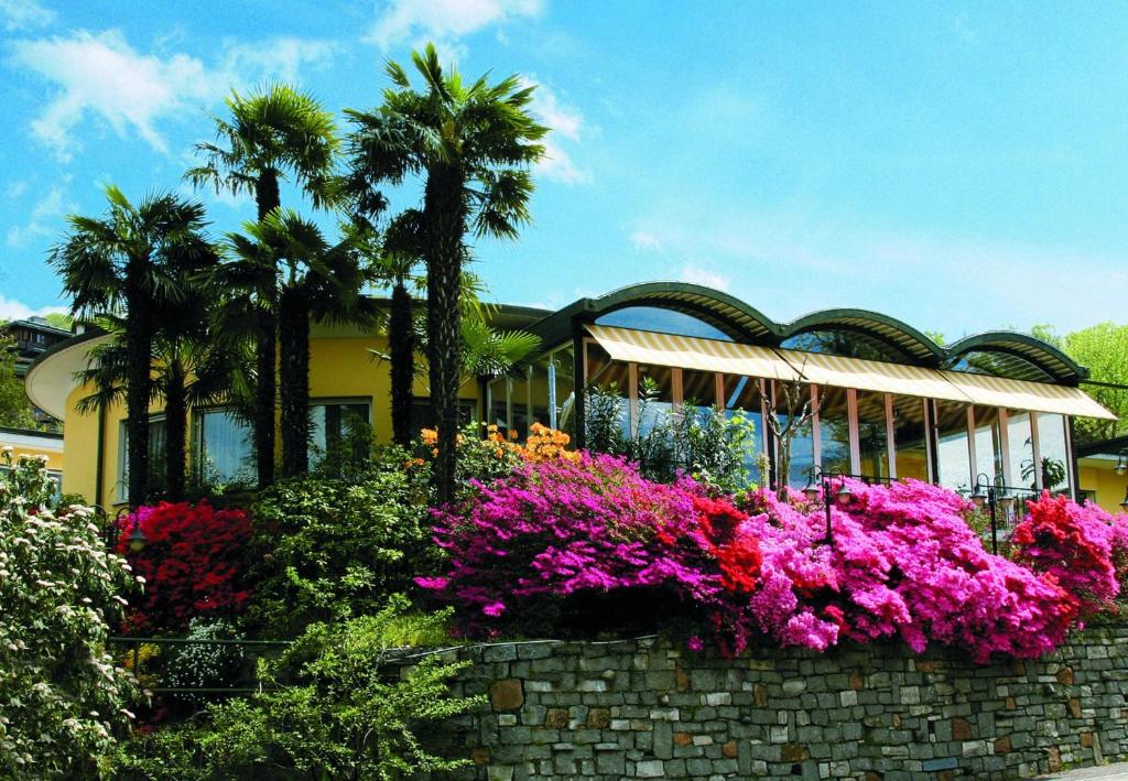 uma casa com palmeiras e flores em frente em Hotel Vezia em Lugano