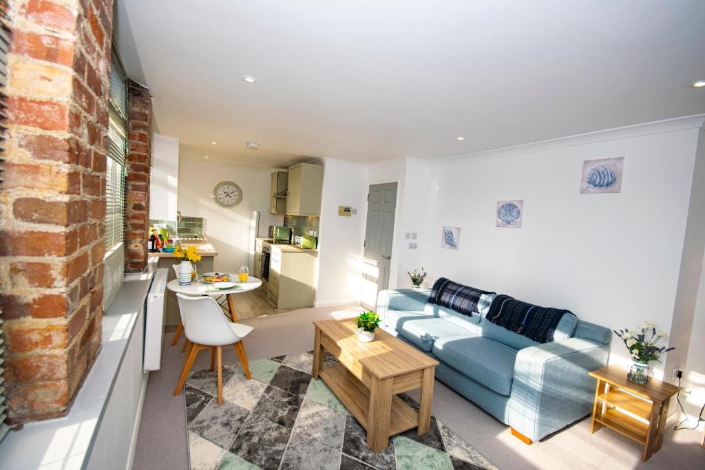 a living room with a blue couch and a table at Lighthouse Lofts - Godrevy in Camborne