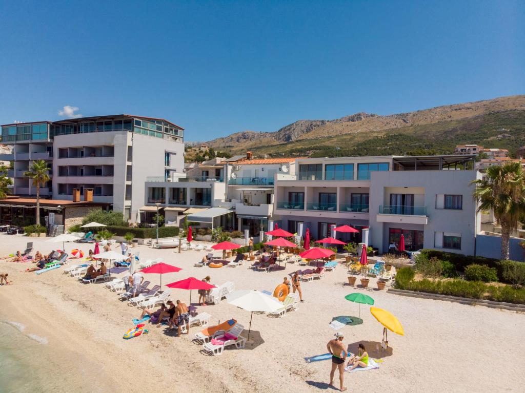 un gruppo di persone seduti su una spiaggia con ombrelloni di Luxury rooms Beach Mediteran a Podstrana