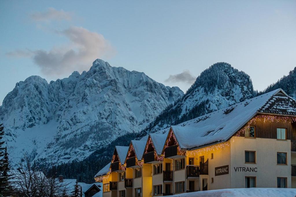 een hotel met sneeuw bedekte bergen op de achtergrond bij Vitranc Apartments in Kranjska Gora