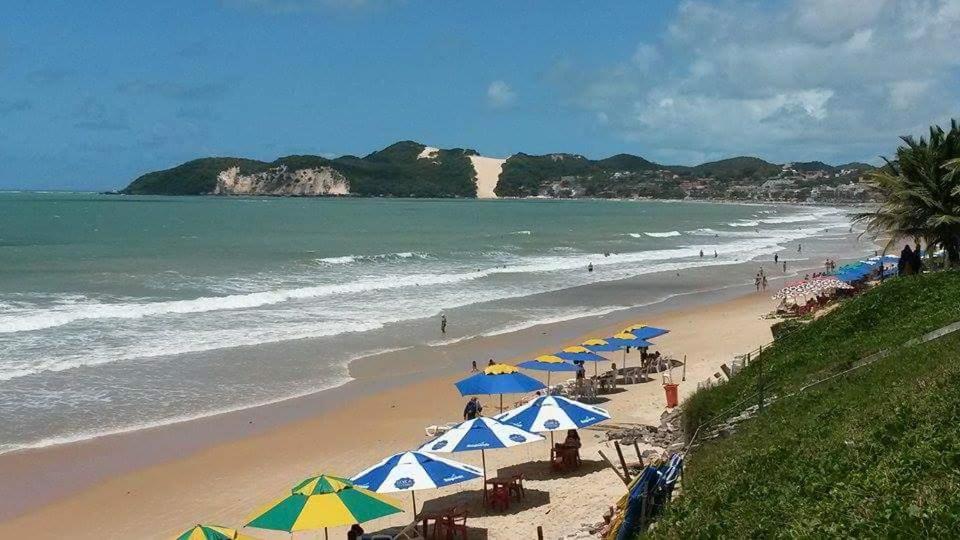 una spiaggia con ombrelloni e sedie e l'oceano di Araça Flat Natal Prime - Beira Mar a Natal