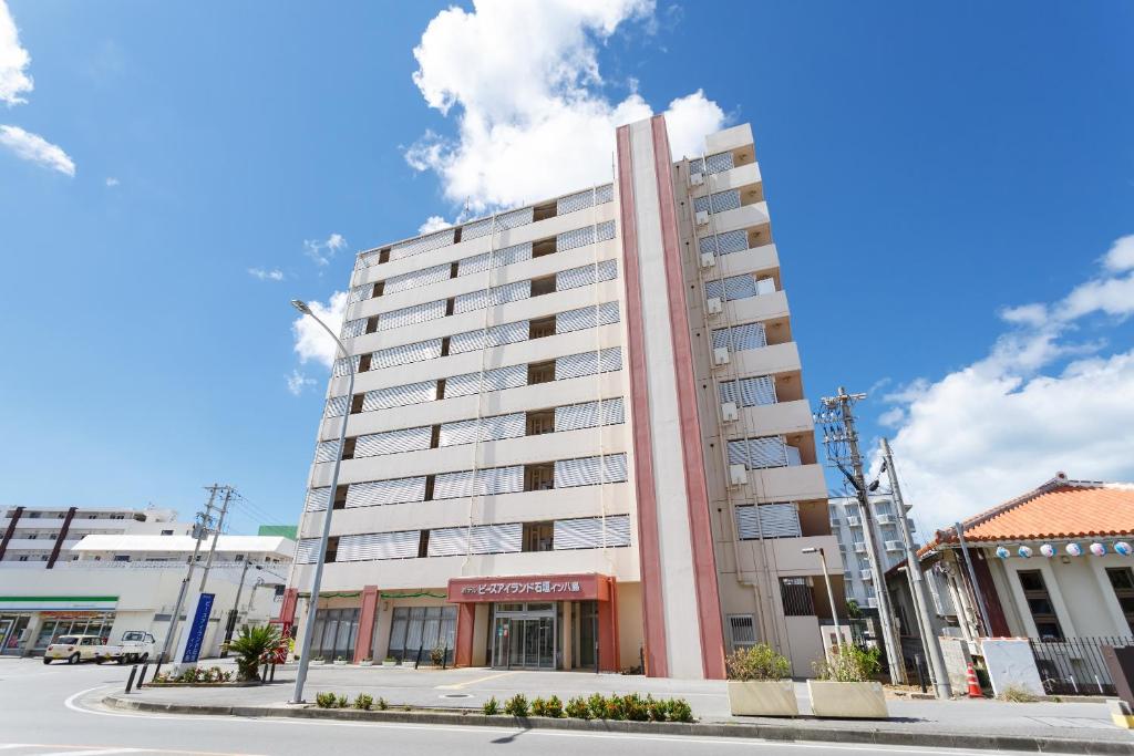 een hoog wit gebouw in een stadsstraat bij Hotel Peace Island Ishigaki in Yashima in Ishigaki Island