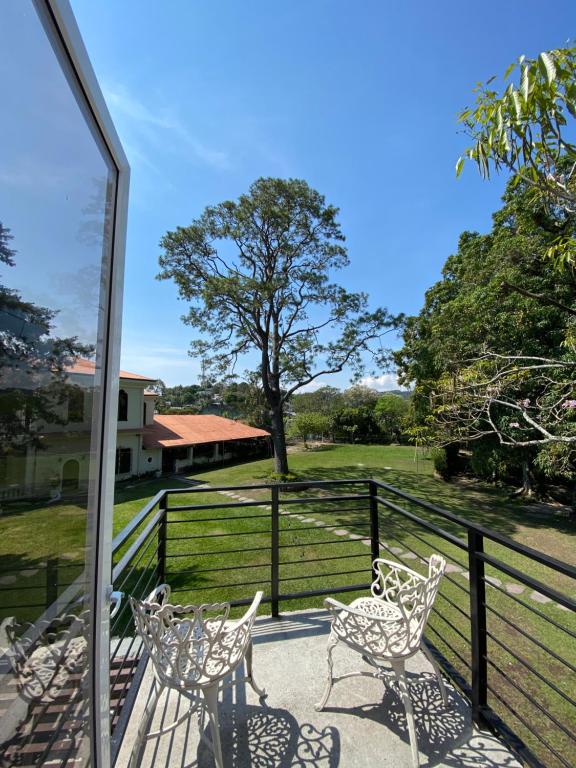 a porch with chairs and a fence and a field at Hotel Finca San Nicolas in San Salvador