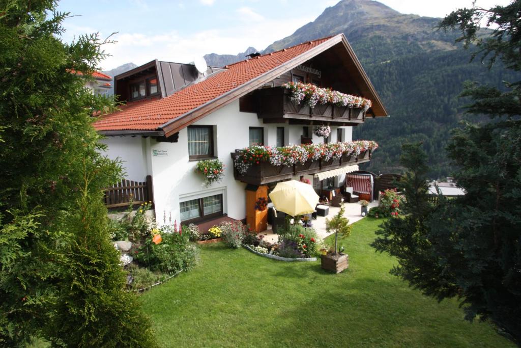 Une grande maison blanche avec des fleurs dans la cour dans l'établissement Haus Sonnenhang, à Sölden